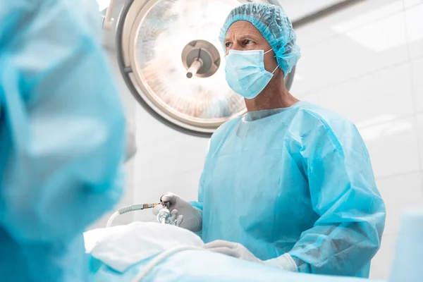 严肃的外科医生站在手术室时皱着眉头 — 图库照片