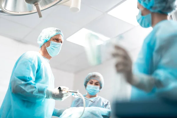 Хирург смотрит на медсестру при использовании лапароскопа во время операции — стоковое фото