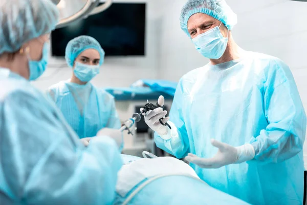 Медсестра дает врачу лапароскопический инструмент во время операции — стоковое фото