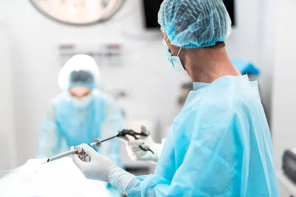 Chirurg mit laparoskopischem Instrument schaut Krankenschwester im Operationssaal an — Stockfoto