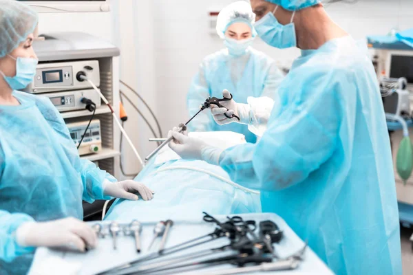 Cirujano sosteniendo instrumento laparoscópico en quirófano — Foto de Stock