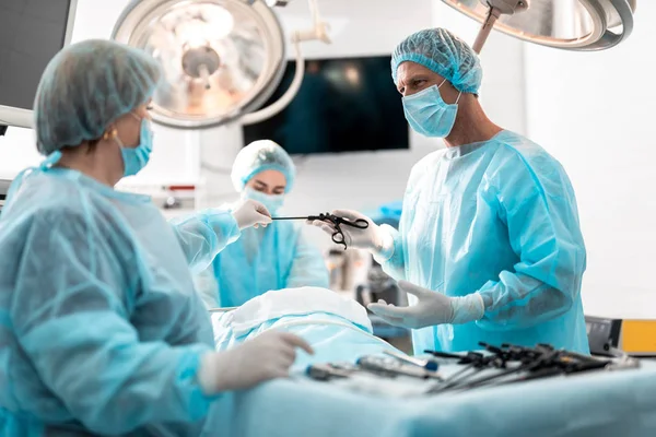 Krankenschwester in sterilen Handschuhen übergibt laparoskopisches Instrument an Arzt — Stockfoto