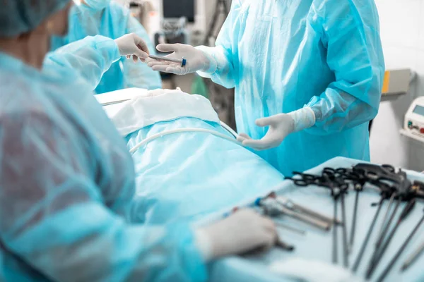 Krankenschwester steht am Tisch mit laparoskopischen Werkzeugen und unterstützt den Chirurgen — Stockfoto