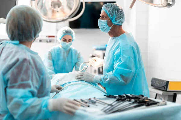 Cirujano en bata azul usando laparoscopio durante la operación quirúrgica — Foto de Stock