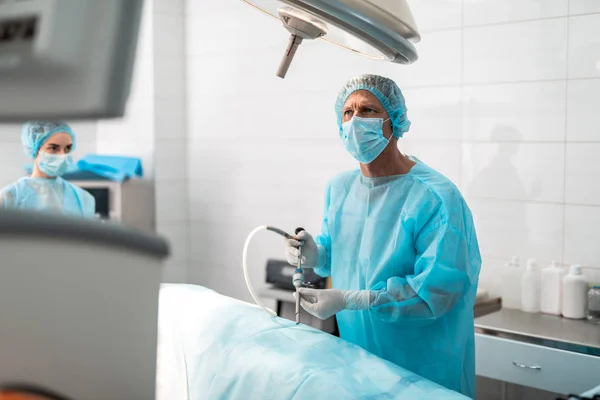 Chirurg mit Laparoskop und Blick auf Monitor während chirurgischer Operation — Stockfoto