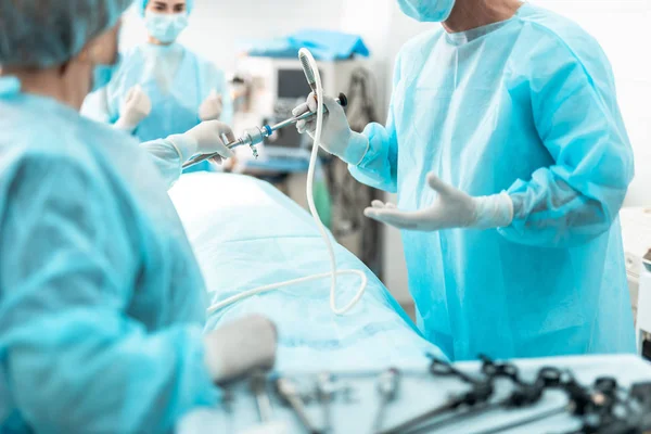 Enfermeira dando laparoscópio ao médico durante a operação cirúrgica — Fotografia de Stock