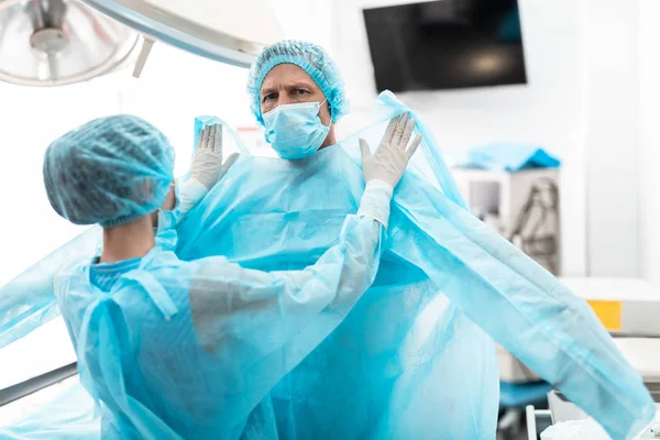 Assistent hilft Arzt bei der Vorbereitung auf chirurgische Operation — Stockfoto