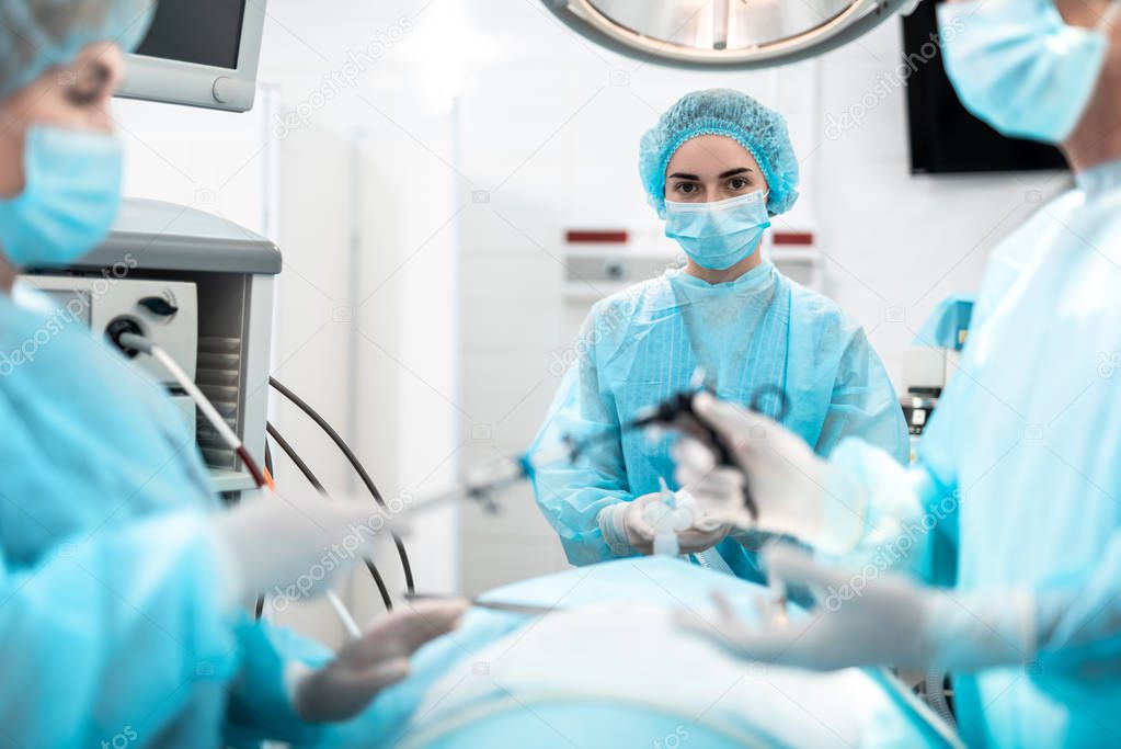 Nurse holding oxygen mask on patient face during surgical operation