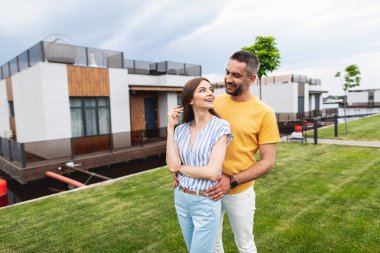 Neşeli kadın erkek arkadaşı tarafından kucakladı ona gülümseyerek bakıyor. Küçük binanın önünde duruyorlar. Kopya alanı sol tarafında