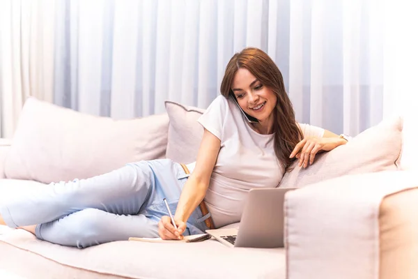 Elfoglalt vidám nő írás, miközben a kanapé — Stock Fotó