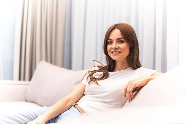 Fröhliche junge Dame auf der Couch im Inneren — Stockfoto