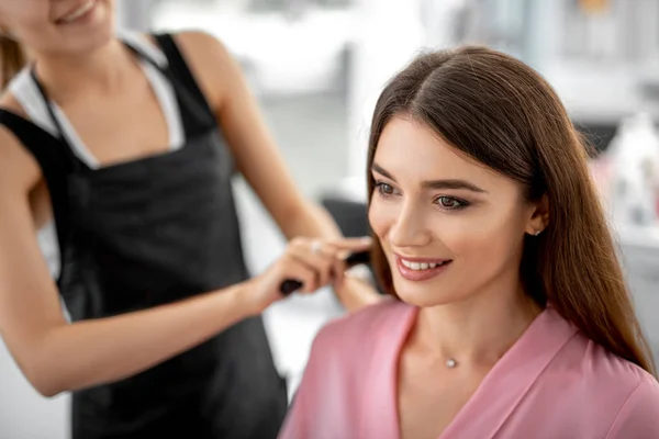 Sorriso cabeleireiro feminino fazendo styling para a mulher — Fotografia de Stock