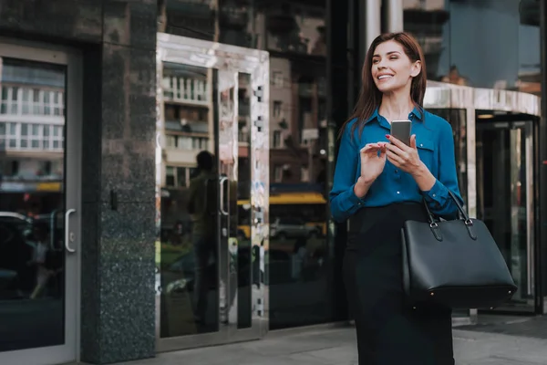 Concept of success and well-being. Waist up portrait of smiling business lady in stylish cloth going on work. Copy space on left