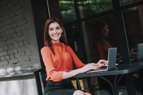 Smiling business woman work on laptop in cafe