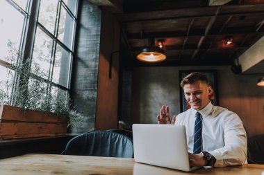 Gülümseyen adam kafede dizüstü skype tarafından sohbet