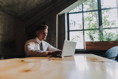 Kafede dizüstü bilgisayar ile oturan genç başarılı erkek