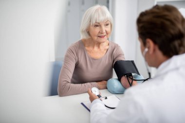 Sakin Bayan gülümseyerek ve kan basıncı ölçme doktor