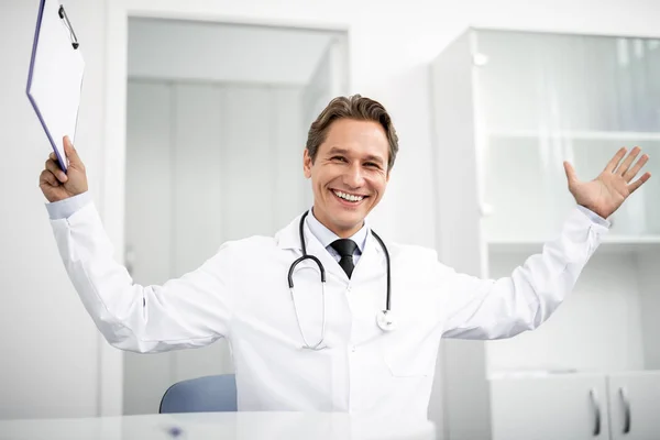 Podekscytowany lekarza rozklejanie schowka i uśmiechając się — Zdjęcie stockowe