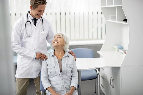 Sandalye ve yanında duran Doktor oturan yaşlı Bayan — Stok fotoğraf