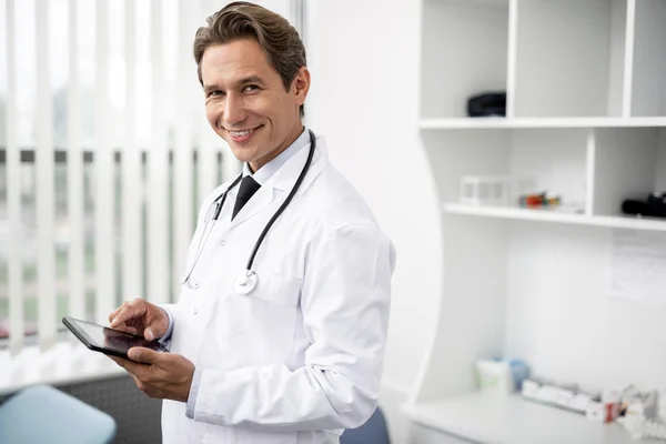 Pozitív orvos mosolyogva állva a modern tabletta — Stock Fotó