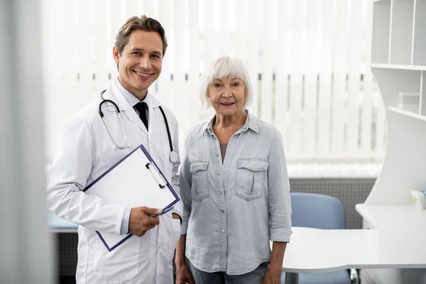Cintura para cima de médico feliz em pé com seu paciente idoso — Fotografia de Stock