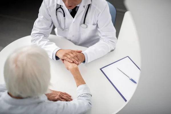 Médico gentil falando com a paciente e segurando a mão — Fotografia de Stock