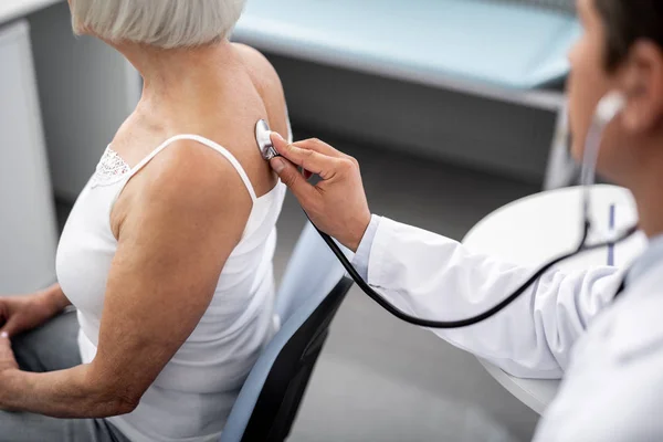 Profesyonel doktor stetoskop hastanın cilt üzerinde koyarak — Stok fotoğraf