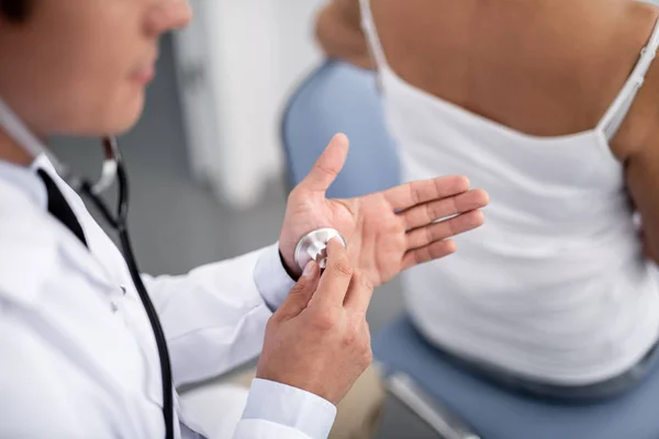 Спокойный доктор кладет стетоскоп себе на руку — стоковое фото