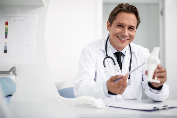 Ystävällinen yleislääkäri, jolla on polvimalli ja hymyilevä — kuvapankkivalokuva