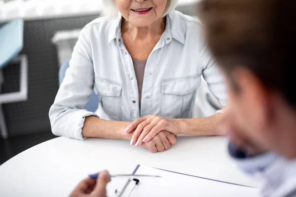 Close up van leeftijd vrouw hand zetten de tabel terwijl het bezoekende beoefenaar — Stockfoto