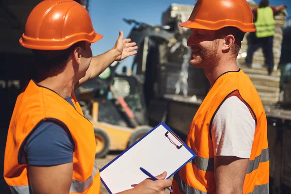 Alegre constructor sonriendo mientras mira a su capataz — Foto de Stock