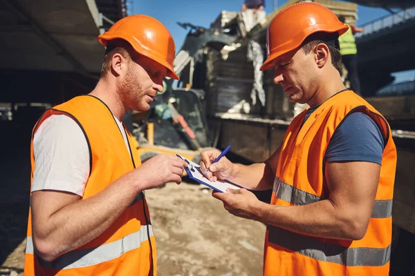 Attento caposquadra che tiene appunti e costruttore a guardarlo — Foto Stock