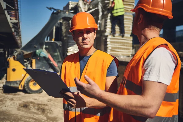 Costruttore premuroso accigliato e guardando il suo collega — Foto Stock