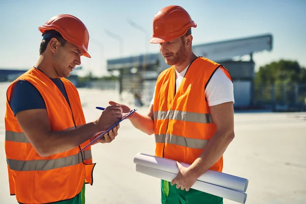 Amistoso constructor hablando y su colega haciendo notas — Foto de Stock