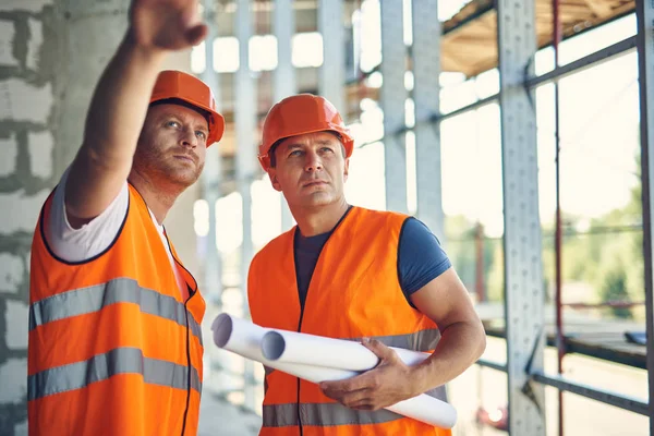 Mesafe içine bakarak iki profesyonel inşaatçılar yakın çekim — Stok fotoğraf