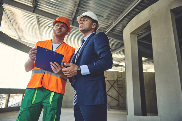Architect with foreman are standing on workplace
