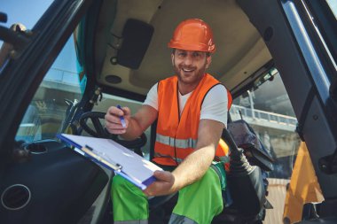 Kask içinde gülümseyen foreman belgeleri veriyor