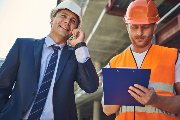 Architect is locating on construction site with worker man