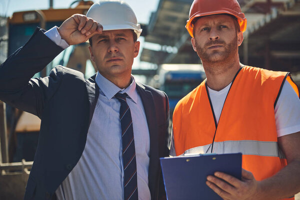 Director with worker are locating at construction site