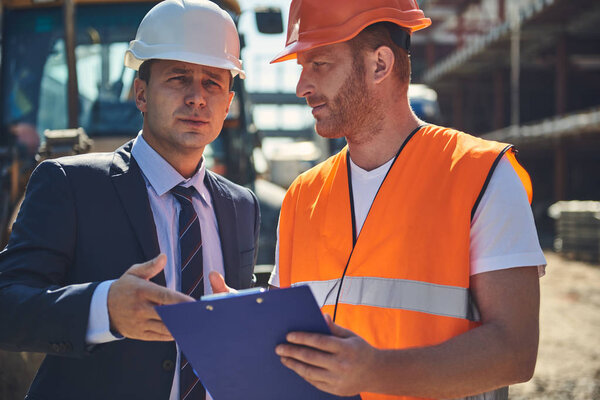 Adult architect is speaking with male worker