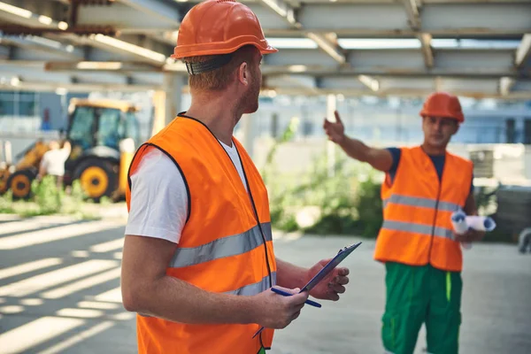 Trabajadores en forma de naranja se comunican en el sitio de construcción — Foto de Stock