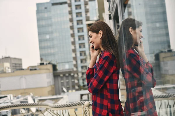 Mujer joven sonriente se encuentra en la terraza — Foto de Stock