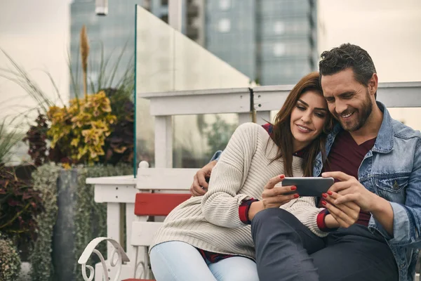 Посміхнена пара дивиться на смартфон на відкритому повітрі — стокове фото