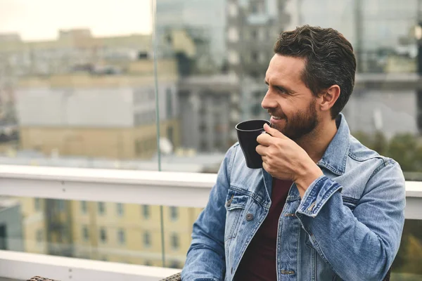 Sonriente hombre con barba está sosteniendo la taza en la mano — Foto de Stock