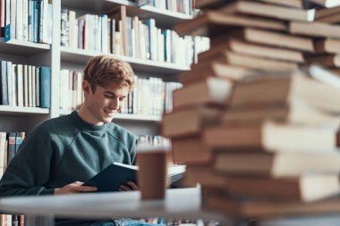 Masada oturan ve ilginç bir kitap okuma sakin genç adam