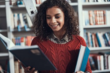 Gülümseyen ve onun elinde kitap bakarak kıvırcık genç bayan
