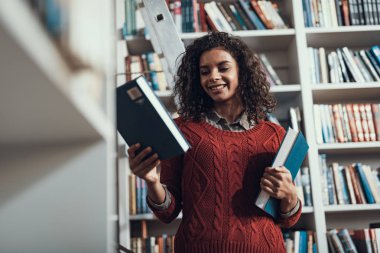 Genç Bayan kütüphanede kitap seçerken memnun arıyorum