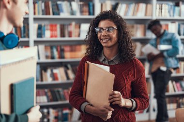 Onu öğrencilik ile ayakta ve gülümseyerek çok kıvırcık Bayan