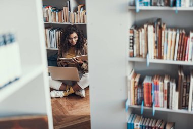 Meraklı kadın Kütüphane yerde otururken notlar arıyorum