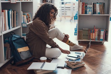 Katta oturan ve modern dizüstü kullanarak mutlu kıvırcık Bayan